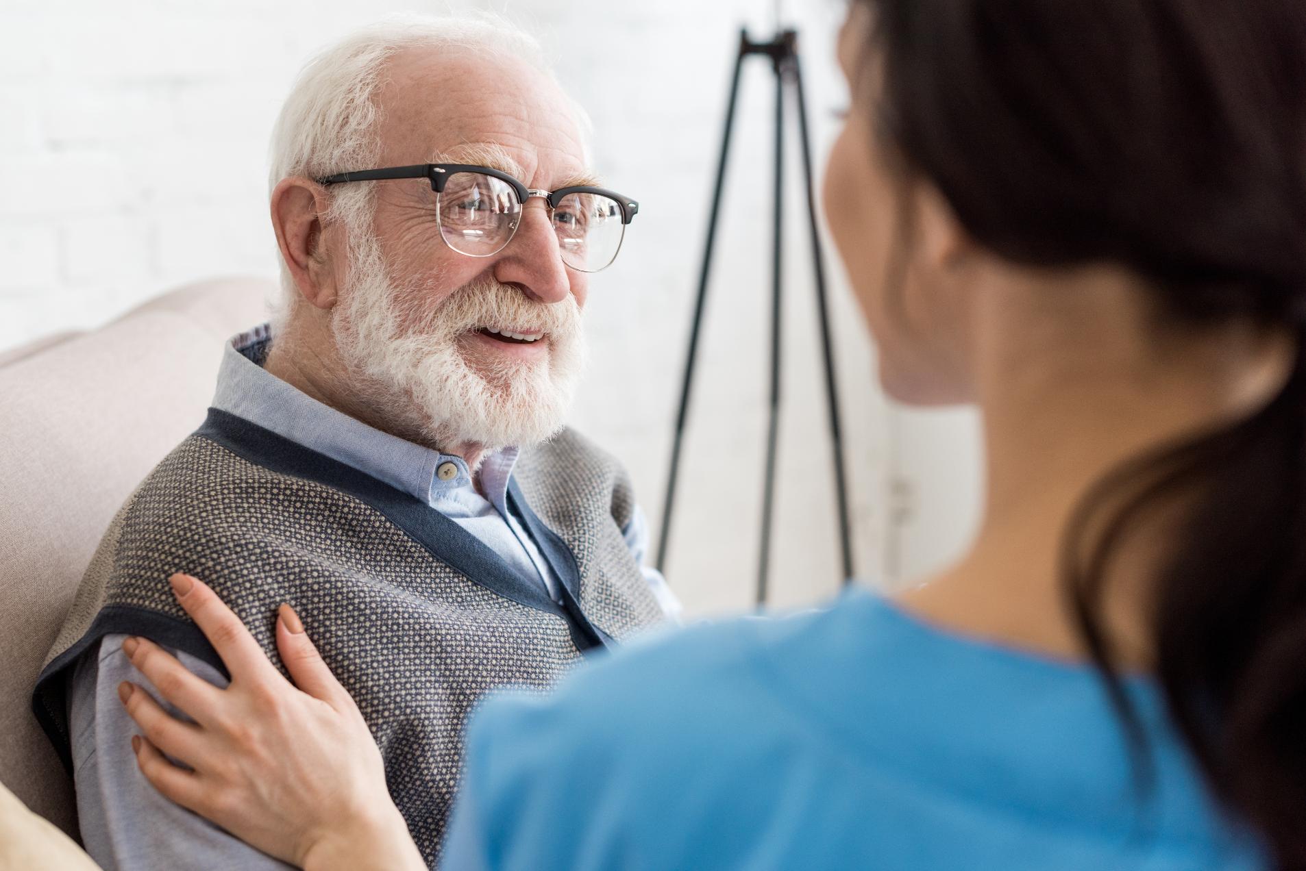 nurse with her hand on an elderly man's shoulder